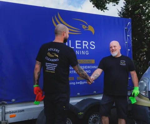 Zwei Mitarbeiter von Adlers Cleaning vor dem Firmenanhänger
